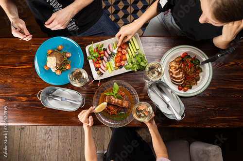 Group of people eating together and drinking wine in a restaurant top view