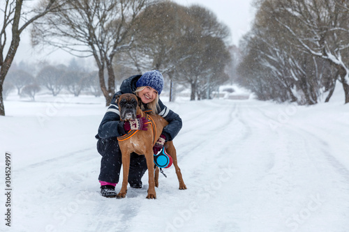 Woman with a dog on a walk in snowy weather. Love and friendship.