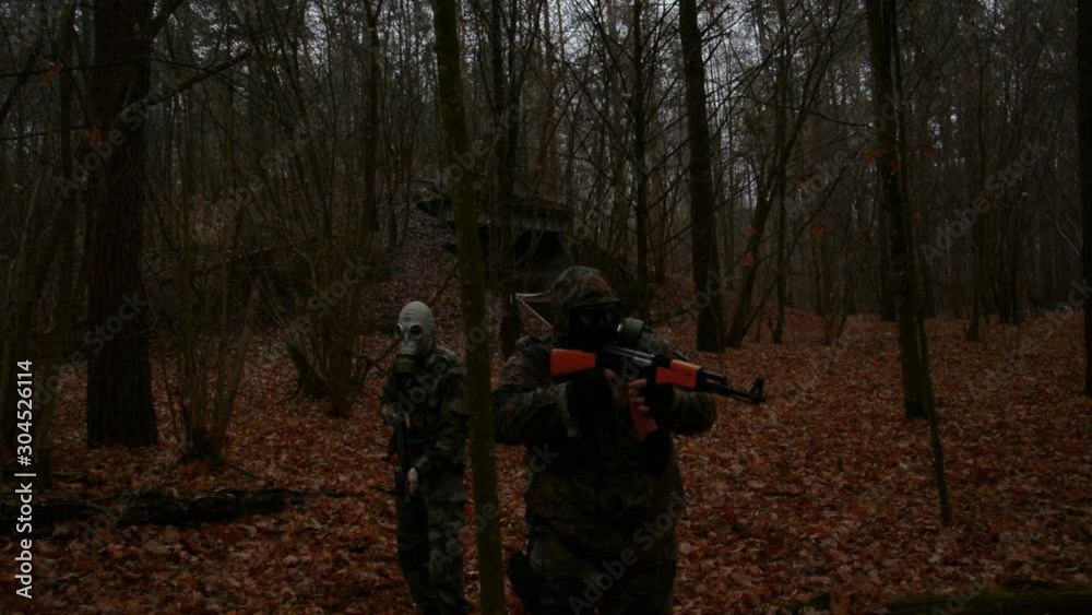 Two Russian soldiers in a gas mask with weapons move through the evening forest Two Russian soldiers in a gas mask with weapons move through the evening forest