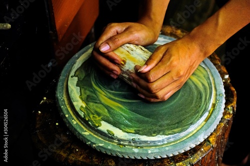 Woman hands grinding Thanaka (A yellowish-white cosmetic paste made from ground bark) on stone slab, The culture of Myanmar. photo