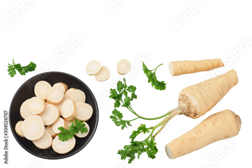 fresh parsley root with slices and parsley in a black plate isolated on white background. top view
