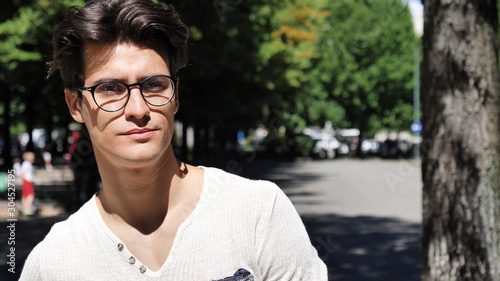 Stylish Young Handsome Man Standing in City Park, Looking at Camera