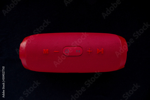 Wireless music speaker. Red bluetooth speaker on black background. Control and volume buttons. photo