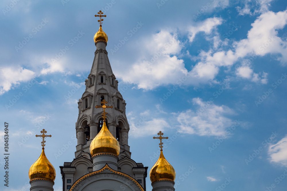 Golden domes and bell tower of the Orthodox Church on a background of cloudy sky