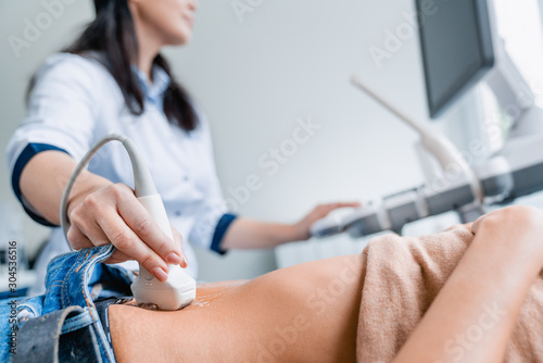Close up of female doctor doing ultrasound probe on patient stomach in medical clinic