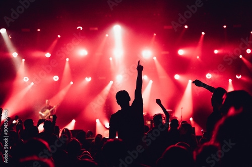 cheering crowd of unrecognized people at a rock music concert. crowd in front of bright stage lights. Concert audience at music concert. Smoke, concert spotlights.