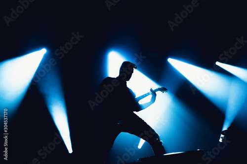 Guitarist plays solo. silhouette of guitar player in action on music stage. popular music rock band performs on stage.