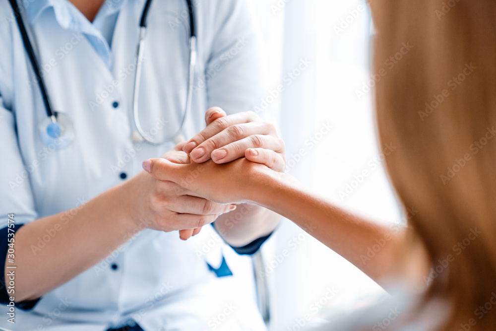 Close up of doctor holding young woman's hand at hospital Close up of doctor holding young woman's hand at hospital