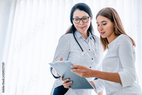Woman doctor and her patient looking at tablet together and discussing photo