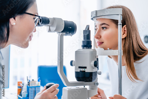 Side view shot of female doctor and patient in ophthalmology clinic