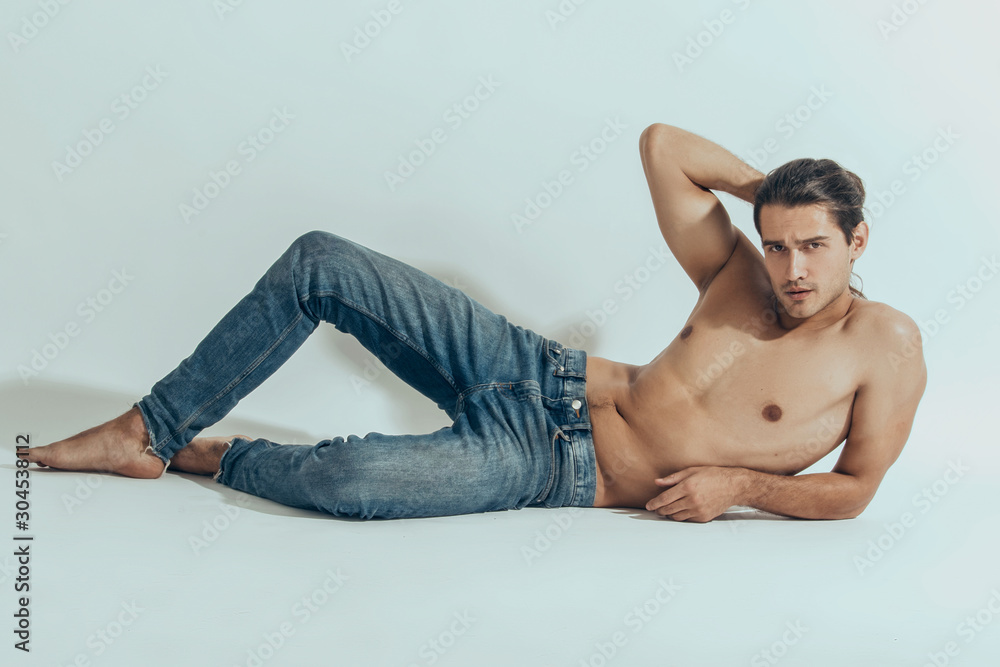 Muscle strong beautiful stripped male model in denim jeans on white isolated font background with shadow Muscle strong beautiful stripped male model in denim jeans on white isolated font background with shadow