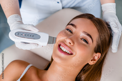 Smiling caucasian female on ultrasound facial beauty treatment