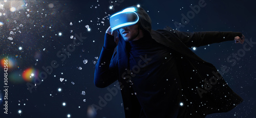 Young man having virtual reality experience. Guy using VR helmet. Augmented reality, future technology, game concept. Rainbow lights, flares.