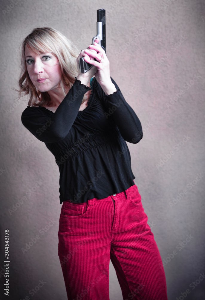 Empowered mature woman holds her loaded gun for self defense. Empowered mature woman holds her loaded gun for self defense.