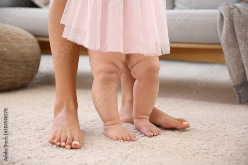 Mother teaching her little baby to walk at home