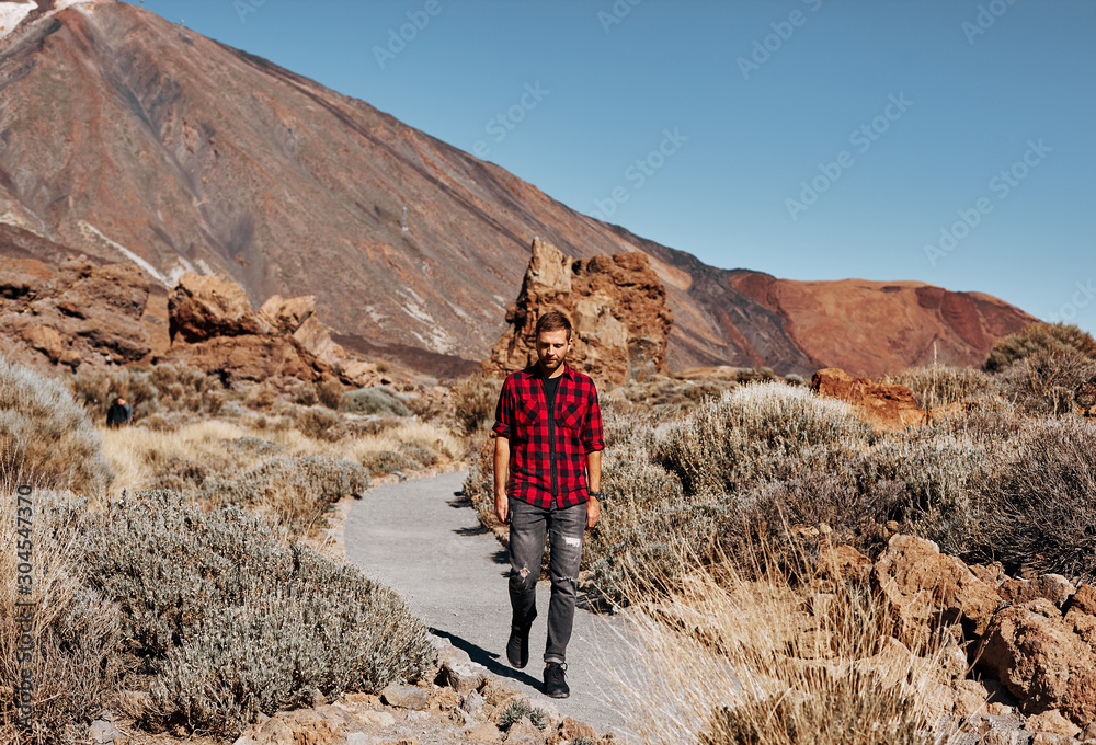 Man on a mountains background. Amazing landscape nature on a summer sunny day. Male fashion model. 