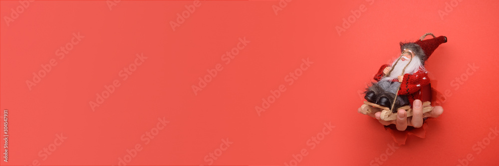  Hand give red and white striped gift box on torn red paper wall. Copy space aside for your advertising and offer or sale content.