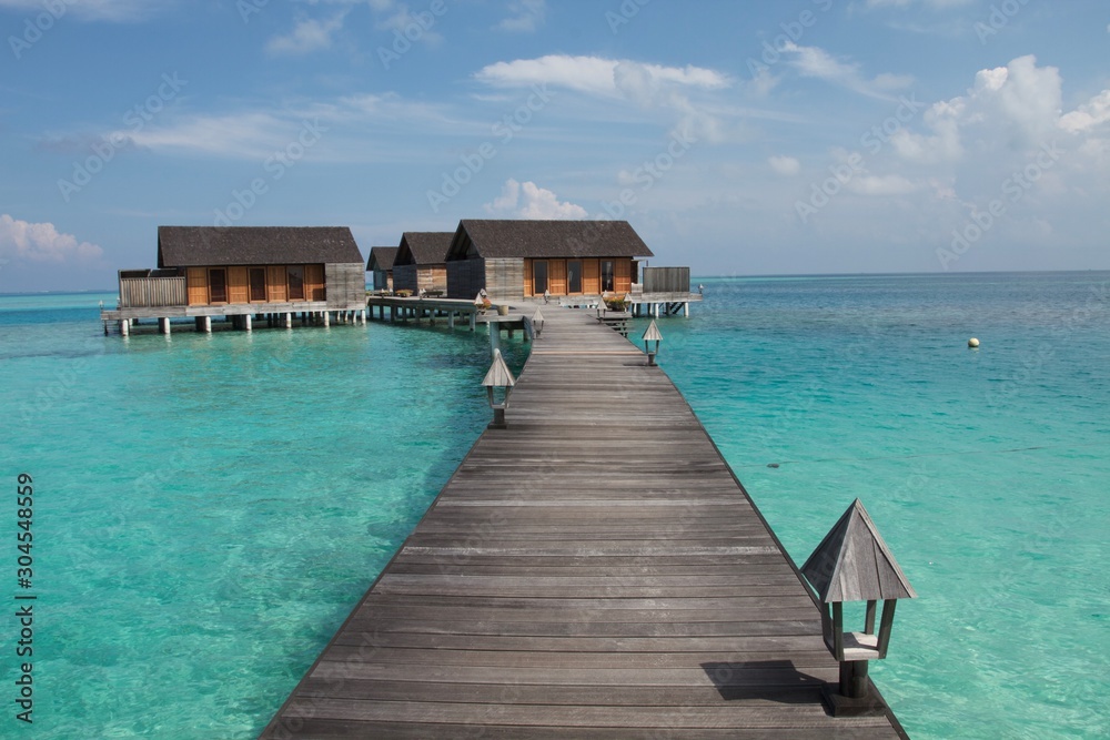 jetty on the sea with water villas bungalows at the end of a wooden walkway, Maldives 