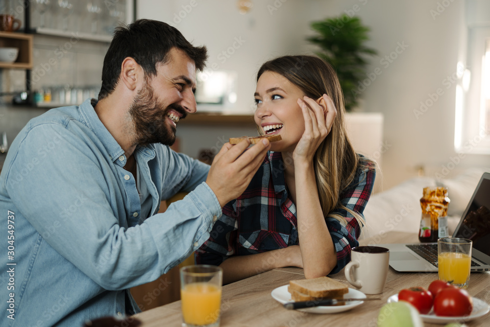 Happy woman being fed by her boyfriend during breakfast time at home Happy woman being fed by her boyfriend during breakfast time at home