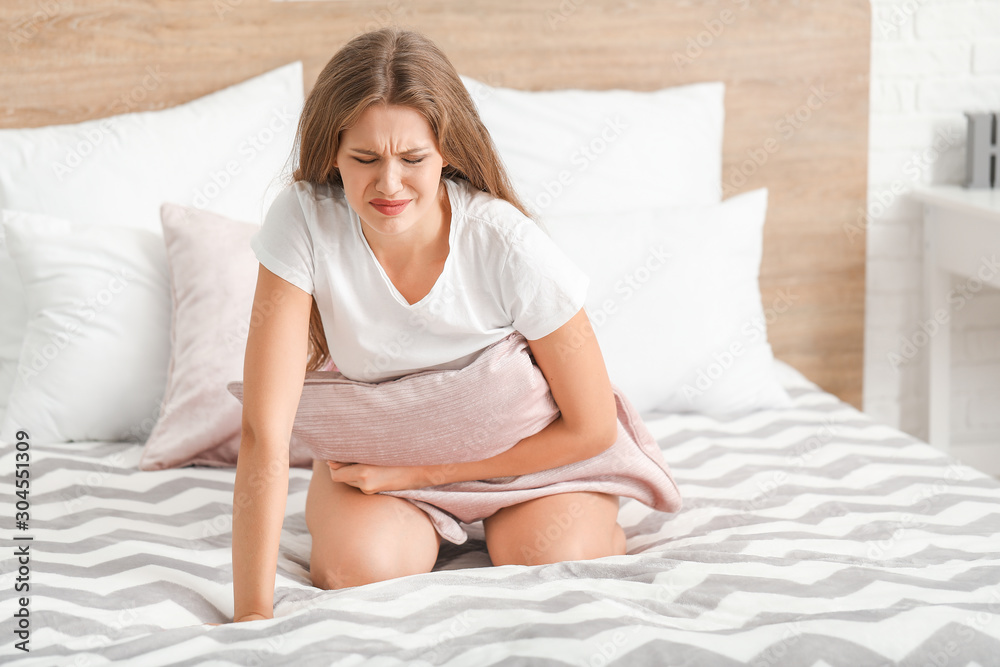Young woman suffering from abdominal pain at home Young woman suffering from abdominal pain at home