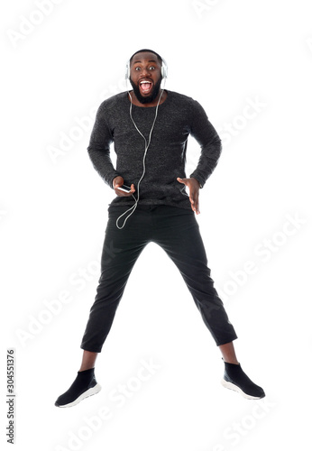 Emotional African-American man listening to music on white background