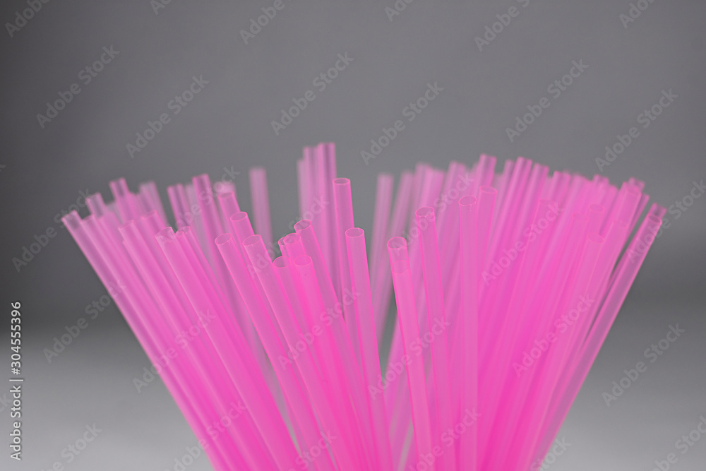 Pink plastic straws for use with drinks such as soft drinks, juices and alcohol on gray background Pink plastic straws for use with drinks such as soft drinks, juices and alcohol on gray background
