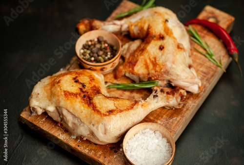 Two fried chicken legs on a stone background with spices, ready to eat © александр таланцев