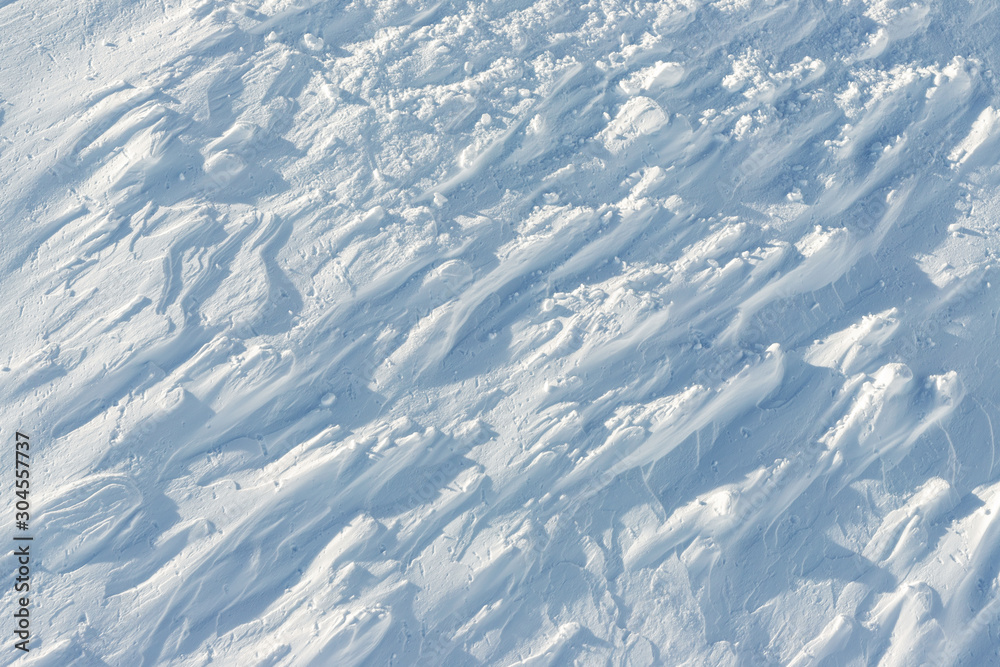 Fototapeta premium Snowy abstract off-piste skiing backround with ski and snowboard trails and tracks on new virgin powder snow. morning sunrise or evening sunset time at alpine mountain resort