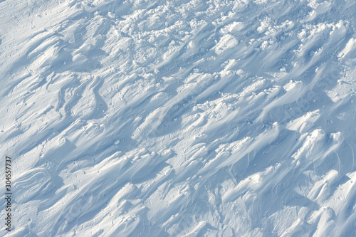 Snowy abstract off-piste skiing backround with ski and snowboard trails and tracks on new virgin powder snow. morning sunrise or evening sunset time at alpine mountain resort © Kirill Gorlov