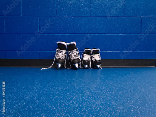 Hockey skates family adult and kid over floor in looker room with copy spac