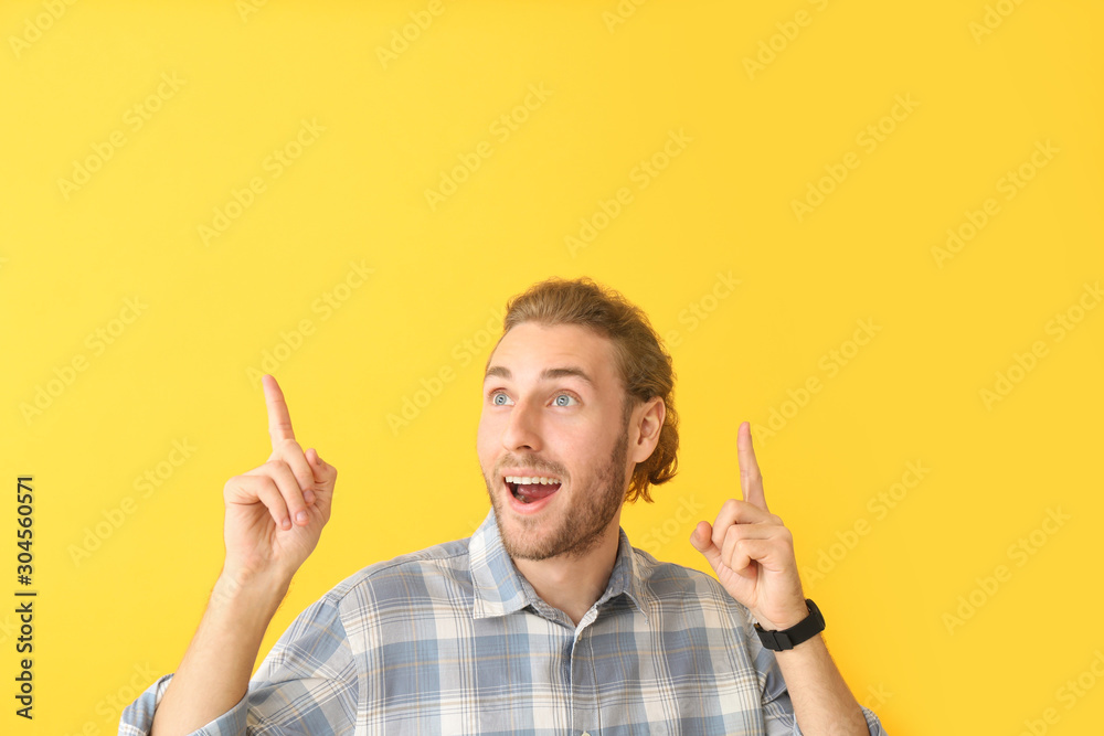 Portrait of happy man pointing at something on color background Portrait of happy man pointing at something on color background
