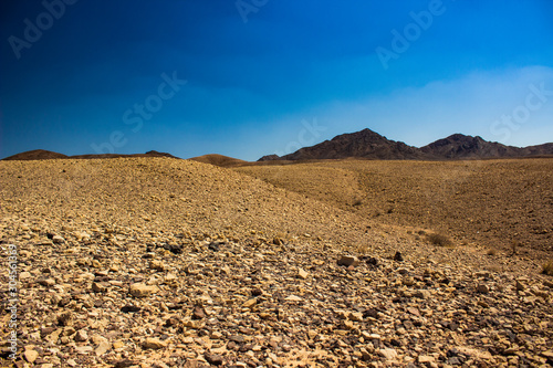 wasteland dry landscape warming environment view with rocky stone ground and desert hills background 