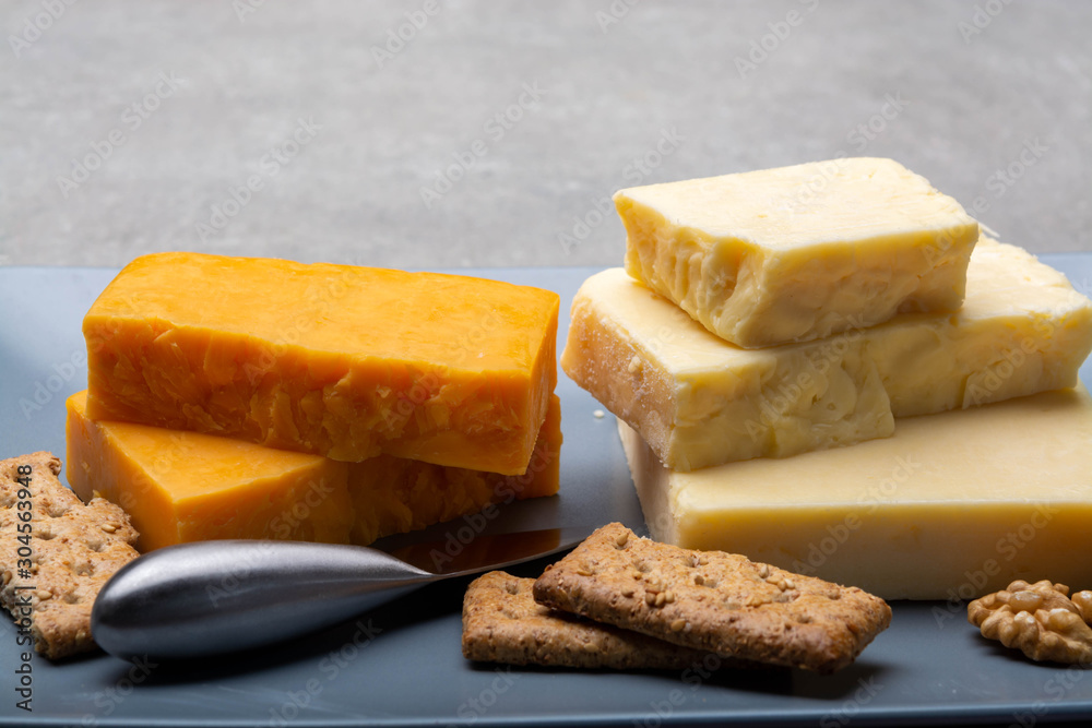 Cheese collection, matured and orange original British cheddar cheese in blocks served on grey plate