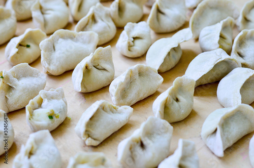 Chinese Uncooked Dumplings Placed on Wooden Board. The Dumplings, called Jiaozi in Chinese, is a popular traditional Chinese food, especially during Chinese New Year.