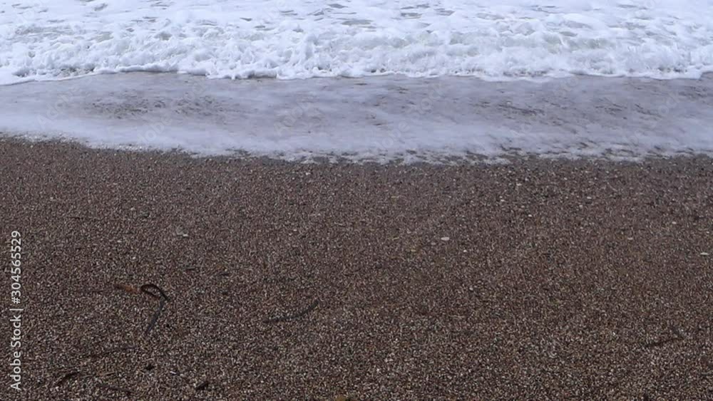 Waves slowly rush onto the yellow sand of the beach. Low angle. Waves slowly rush onto the yellow sand of the beach. Low angle.