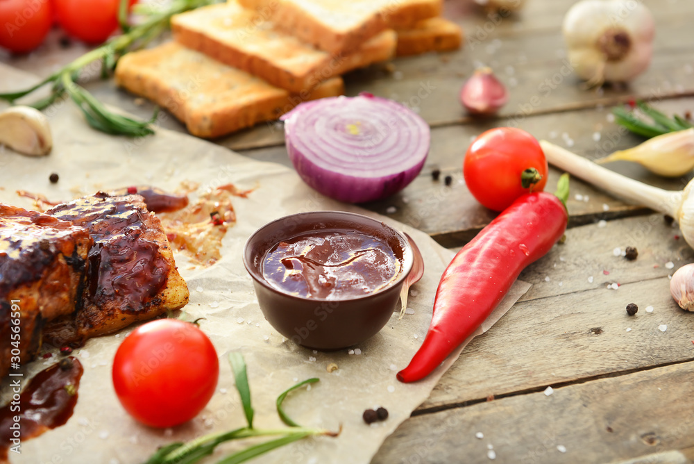 Tasty grilled meat with barbecue sauce, vegetables and spices on table