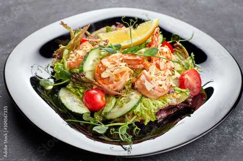 Vegetable salad with shrimp, on a black background