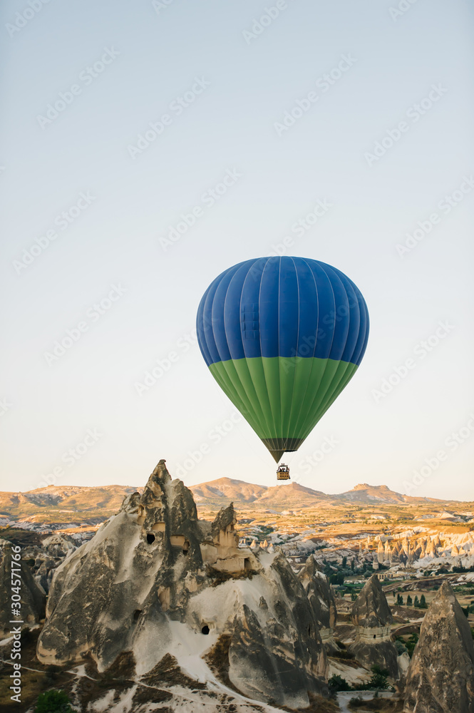 Many colorful hot air balloons flight above mountains - panorama of Cappadocia at sunrise. Wide landscape of Goreme valley in Cappadocia - billboard background for your travel concept in Turkey.
