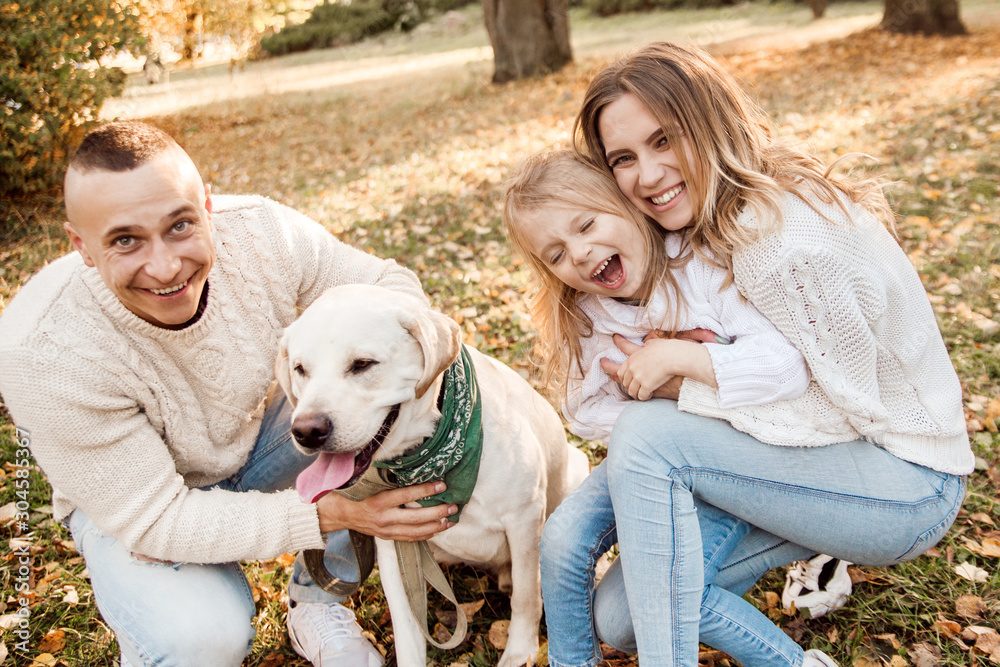 Happy beautiful family with dog labrador is having fun are sitting on green grass in park. Happy beautiful family with dog labrador is having fun are sitting on green grass in park.