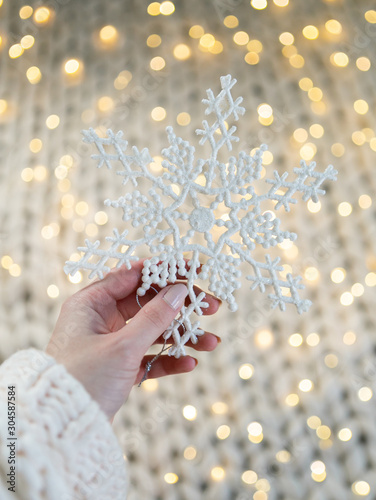 Girl holding snowflake decoration with bokeh Christmas lights in background