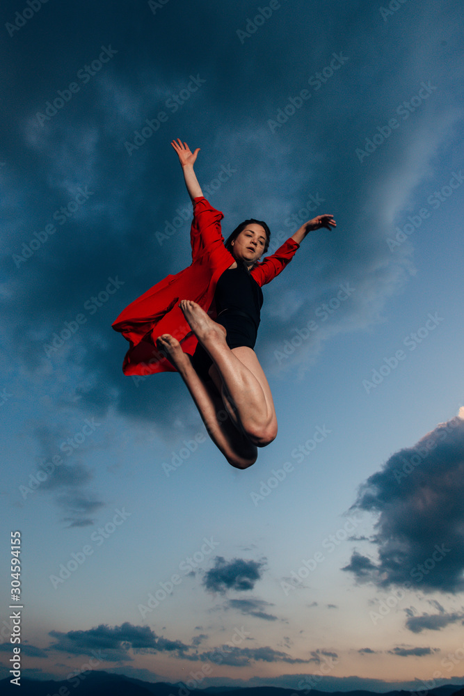 Flexible young woman in ballet figure against blue sky Flexible young woman in ballet figure against blue sky