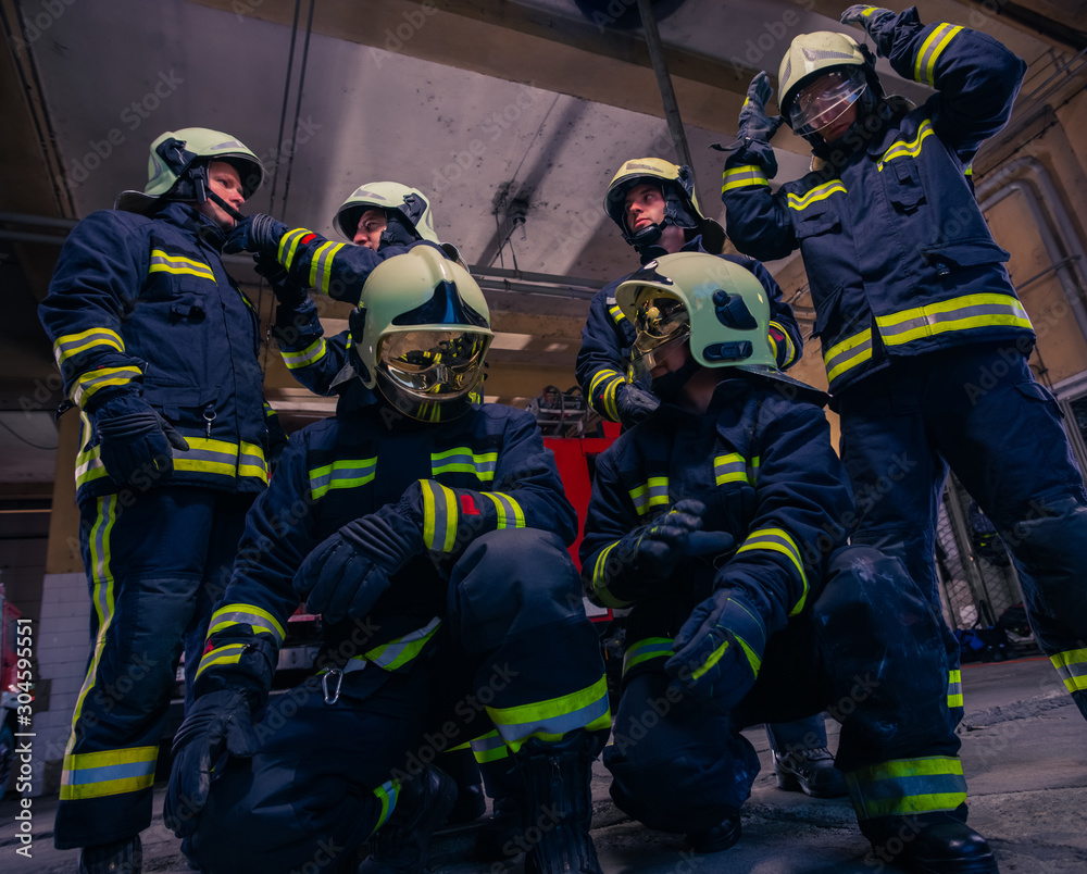 Portrait of group firefighters in front of firetruck inside the fire station Portrait of group firefighters in front of firetruck inside the fire station