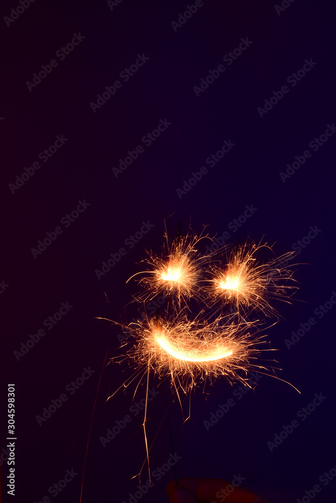 Sparkler emoticon on a dark background. Long exposure