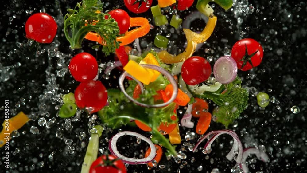 Super Slow Motion Shot of Flying Cuts of Colorful Vegetables and Water Drops on Black background at 1000fps.