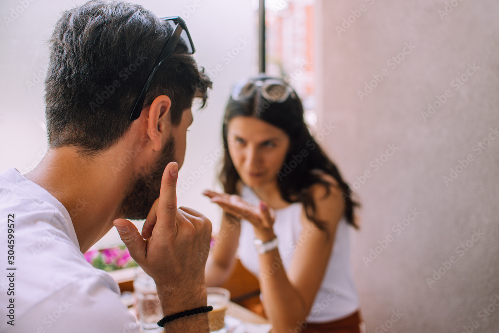Cheerful bearded man flirting with his attractive girlfriend in outdoor restaurant on sunny day Cheerful bearded man flirting with his attractive girlfriend in outdoor restaurant on sunny day