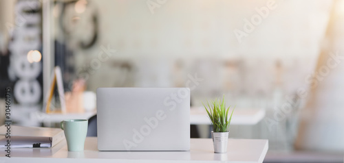 Cropped shot of comfortable workplace with laptop computer and office supplies with sunlight background