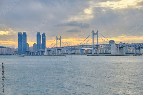 Scenic view of awesome sunset over modern bridge, sea and skyscrapers in Busan in South Korea. Beautiful summer cloudy look of evening in relax place in resort city of Republic of Korea
