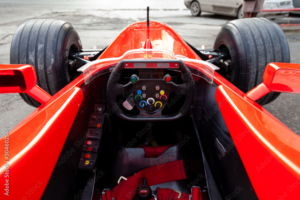 Foto Stock Cockpit and steering wheel view of red Ferrari racing sports  cars for Formula 1 on the street near the garage box. | Adobe Stock