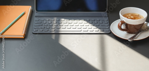 Cropped shot of modern office room with digital tablet, office supplies and a cup of tea photo