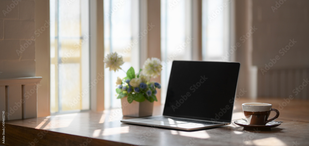 Comfortable workplace with laptop computer, coffee cup and tree pot on wooden table